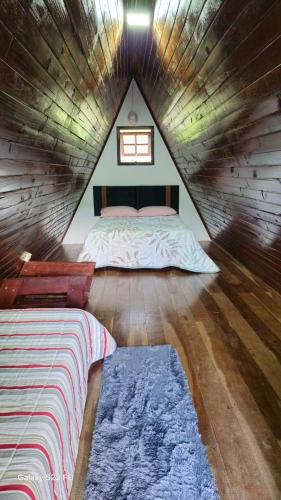 a bedroom with a bed in a wooden house at Chalé Paraíso das Nascentes in Salesópolis