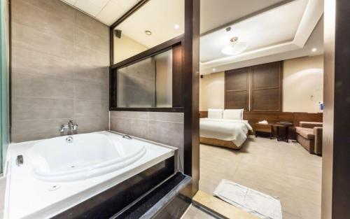 a bathroom with a bath tub and a bedroom at Nowon Ritz Hotel in Seoul