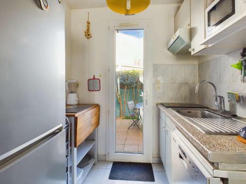 d'une cuisine avec évier et d'une porte donnant sur une terrasse. dans l'établissement Maison mitoyenne 5 pers, chambres climatisées, parking, animaux, wifi inclus - FR-1-326-859, à Marseillan