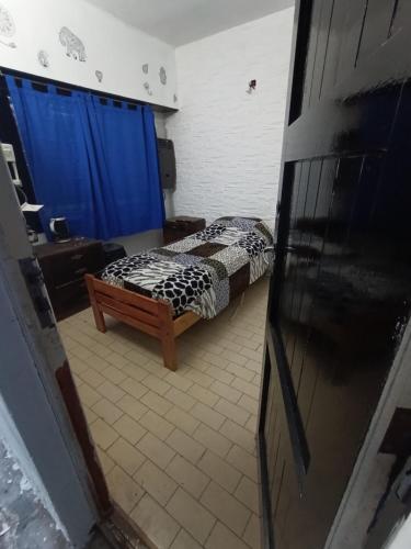 a small bedroom with a bed and a blue curtain at Rincón de mery in Mar del Plata