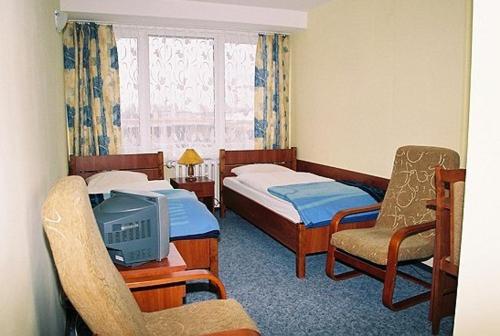 a hotel room with two beds and a tv at Hotel Kujawy in Włocławek