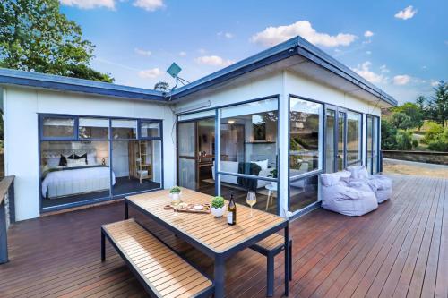 a house with a wooden deck with a table at Goughs Gem in Goughs Bay