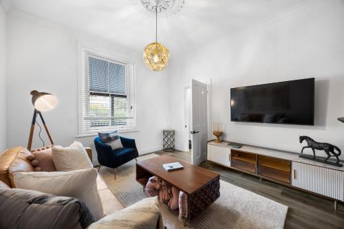 a living room with a couch and a tv at Velvet Cottage - Couple's City Escape with Courtyard in Adelaide