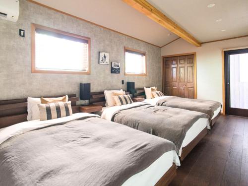 a bedroom with three beds in a room at Monterey House by SANA in Tateyama