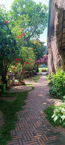 a brick walkway with flowers and tables and a building at Tam Coc Village Bungalow in Ninh Binh