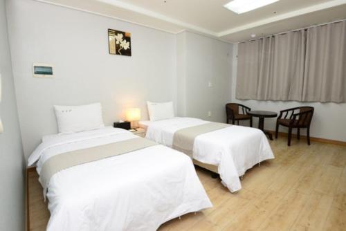 two beds in a white room with a table and chairs at Yeongdeungpo VIP Hotel in Seoul