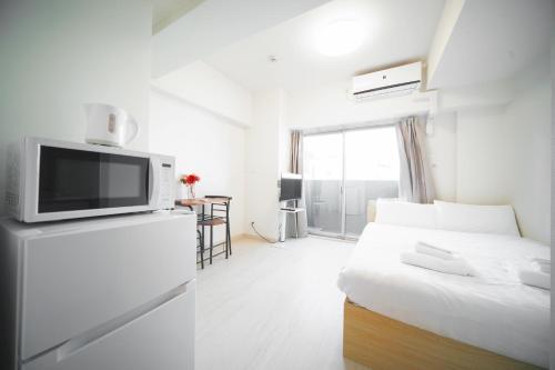 a white room with a bed and a tv at Color Tsuruhashi in Osaka