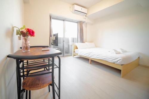 a room with a bed and a table with a vase of flowers at Color Tsuruhashi in Osaka
