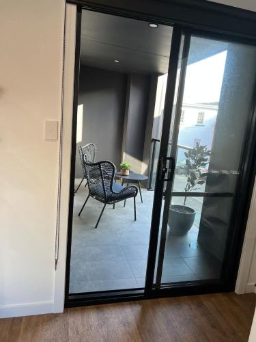 a room with a glass door with a chair and a table at CBD Elizabeth St Modern Townhouse - Secure Parking in Launceston