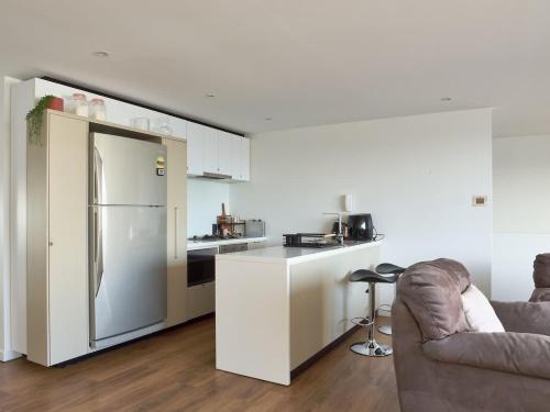 a white kitchen with a refrigerator and a couch at Gateway to The Gorge, Central with Free Parking in Launceston