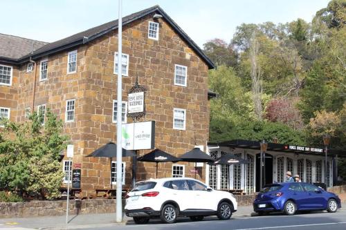 two cars parked in front of a brick building at Gateway to The Gorge, Central with Free Parking in Launceston