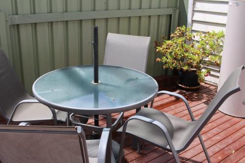 un tavolo in vetro e sedie su una terrazza di Little Gem City Cottage a Invermay