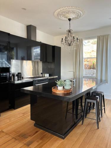 a kitchen with a large black island with a chandelier at Forest Rd Haven with Tamar River Views in Inveresk