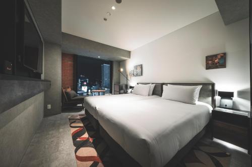 a bedroom with a large white bed and a living room at SAPPORO STREAM HOTEL in Sapporo