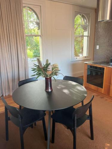 a dining room table with chairs and a vase with a plant at Le Salon Luxury City Apartment with Free Parking in Launceston