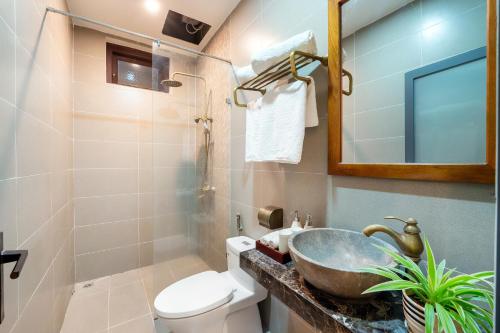 a bathroom with a sink and a toilet and a mirror at Sunset Beach Hoi An in Tân Thành (1)