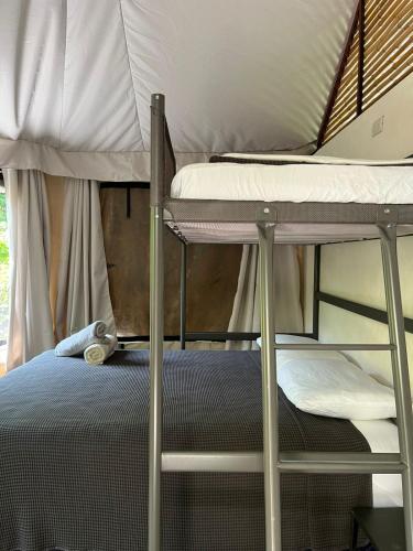 a bedroom with a bunk bed with a ladder and a pillow at Safari tent with private pool close to Manuel Antonio in Matapalo