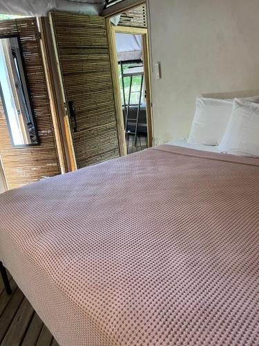 a large bed in a room with a window at Safari tent with private pool close to Manuel Antonio in Matapalo