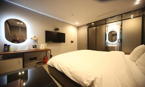 a bedroom with a large white bed and a mirror at Life Style S Hotel in Seoul
