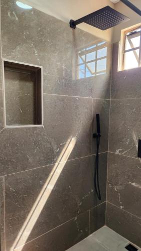 a bathroom with a stone shower with a window at The Layover - 6 Mins from the Airport, Equipped for Long Stays in Piarco