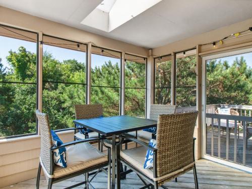 a screened porch with a blue table and chairs at 3041 - The Beach House in Southern Shores