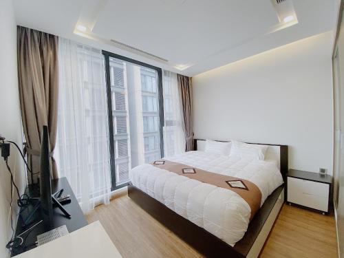 a bedroom with a bed and a large window at Vinhomes Metropolis Hanoi - CitiHome in Hanoi