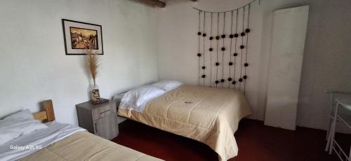 a bedroom with two beds and a table with a lamp at Hostel El Tambo in Ollantaytambo