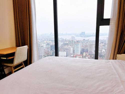 a bedroom with a white bed and a desk and a window at Vinhomes Metropolis Hanoi - CitiHome in Hanoi