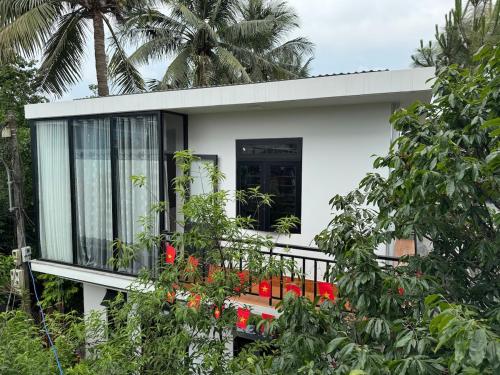 a white house with a balcony with red flowers at Live like a local Homestay in Ấp Tư Tây