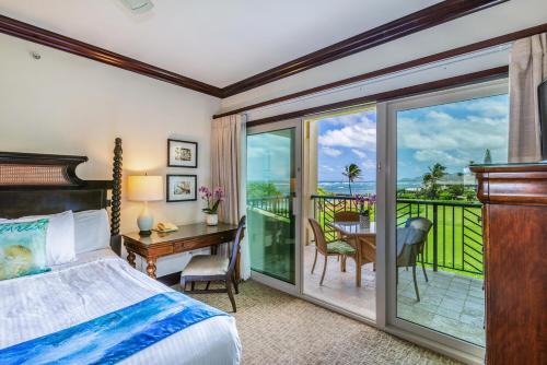 a bedroom with a bed and a desk and a balcony at Waipouli Beach Resort H301 in Wailua