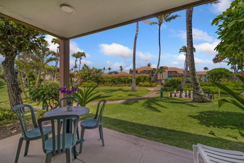 a patio with a table and chairs and palm trees at Pono Kai J107 in Kapaa