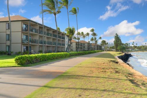 a walkway next to a beach with palm trees at Pono Kai J107 in Kapaa