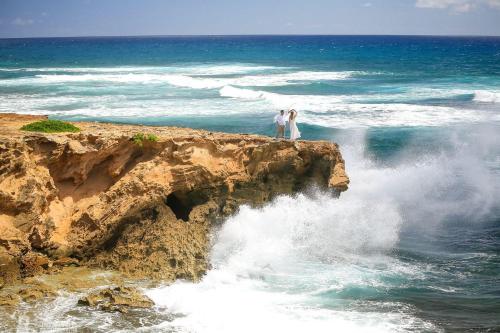 two people standing on a rock in the ocean at Pono Kai J107 in Kapaa