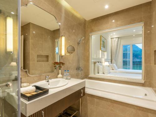 a bathroom with a sink and a tub and a mirror at Legend Valley Hotel Ha Nam in Phủ Lý