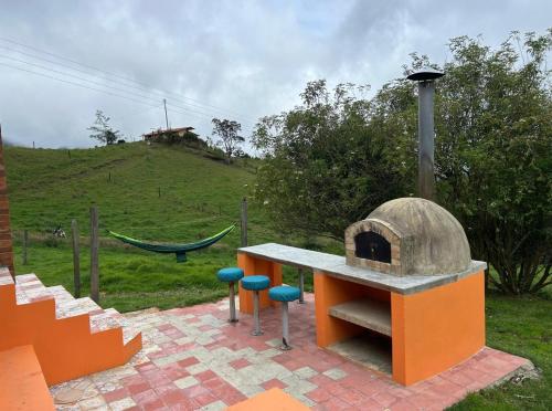 a outdoor oven with stools and a hammock in a field at Descanso y Naturaleza in Bogotá