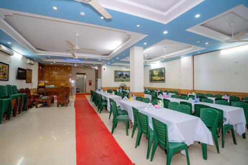 Un salón de banquetes con mesas blancas y sillas verdes. en Khách Sạn Hoàng Minh, en Sầm Sơn