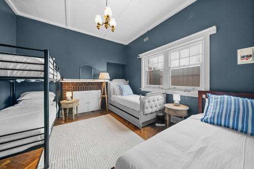 - une chambre avec des murs bleus, 2 lits et une chaise dans l'établissement Belle Escapes - Sea Glass Cottage on the Esplanade, à Henley Beach South