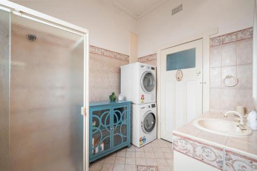une salle de bains avec lave-linge et lavabo dans l'établissement Belle Escapes - Sea Glass Cottage on the Esplanade, à Henley Beach South