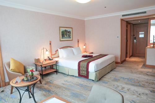 a hotel room with a large bed and a table at Hanoi Daewoo Hotel in Hanoi