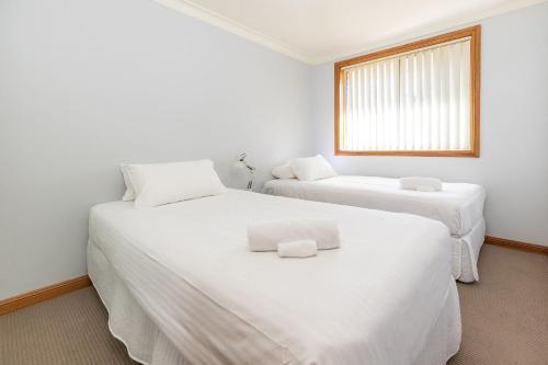 two white beds in a room with a window at Birchgrove Terrace 5 in Tuncurry