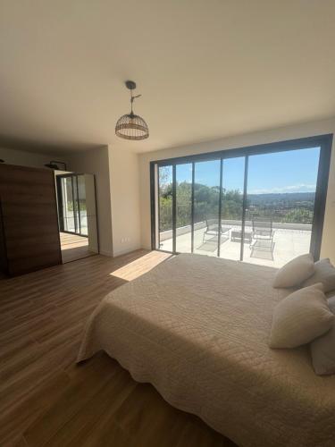 une chambre avec un grand lit et une grande fenêtre dans l'établissement La villa du Clos, à Saint-Paul-de-Vence