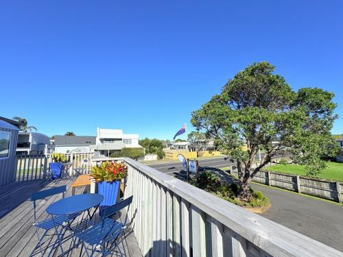 a deck with a table and chairs and a tree at Baileys At The Beach in Whitianga