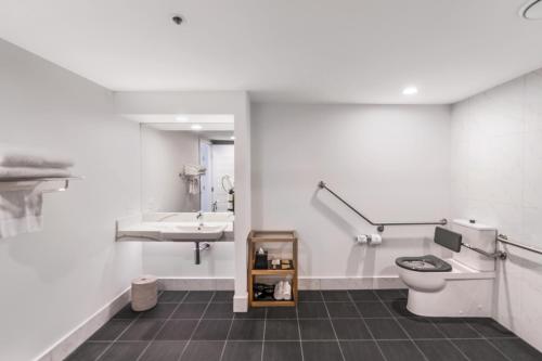 a white bathroom with a toilet and a sink at Pullman Cairns International in Cairns