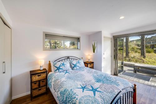una camera da letto con un letto con un piumone blu di Mahanga Dunes Retreat - Mahia Holiday Home a Mahia