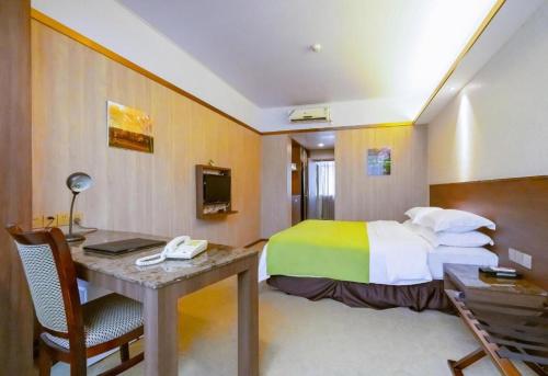 a hotel room with a bed and a desk with a computer at My Pleasant Hotel in Shenzhen