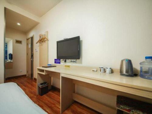 a hotel room with a desk with a tv on the wall at Super 8 Hotel Jinan Railway Station Square in Jinan