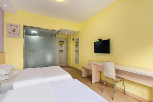 a room with two beds and a desk and a tv at 7 Days Inn Jinan Changqing Jingshi West Road Center in Jinan