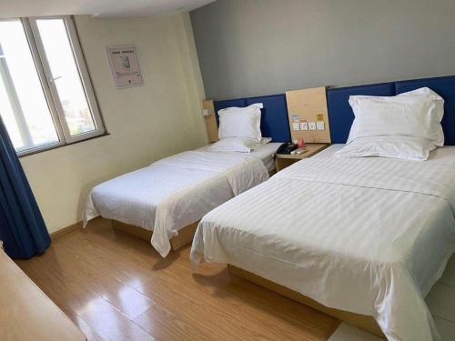 a hotel room with two beds and a window at 7 Days Inn Jinan Changqing Jingshi West Road Center in Jinan