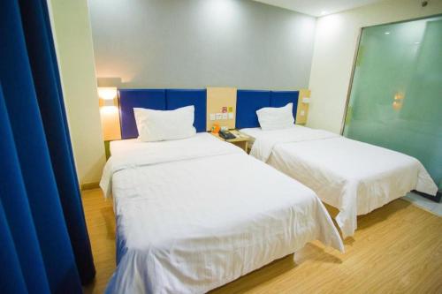a room with two beds with white sheets at 7 Days Inn Jinan Changqing Jingshi West Road Center in Jinan