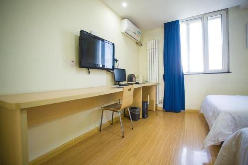 a room with a desk with a television and a bed at 7 Days Inn Jinan Changqing Jingshi West Road Center in Jinan